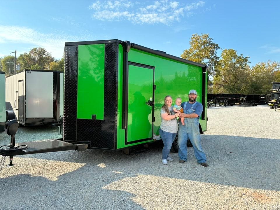 Happy customers with their new green enclosed trailer